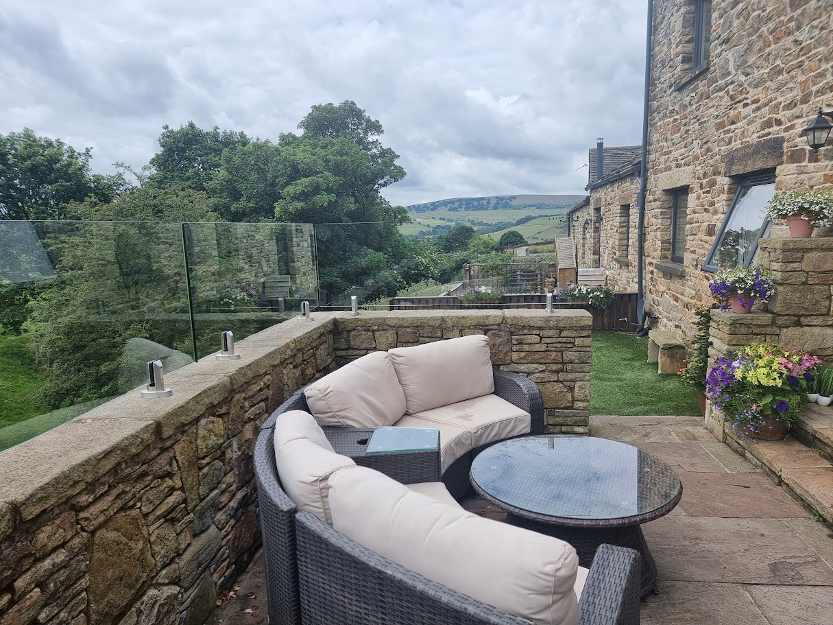 A frameless glass terrace at a New Mills farmyard conversion — Manchester Balustrades installation