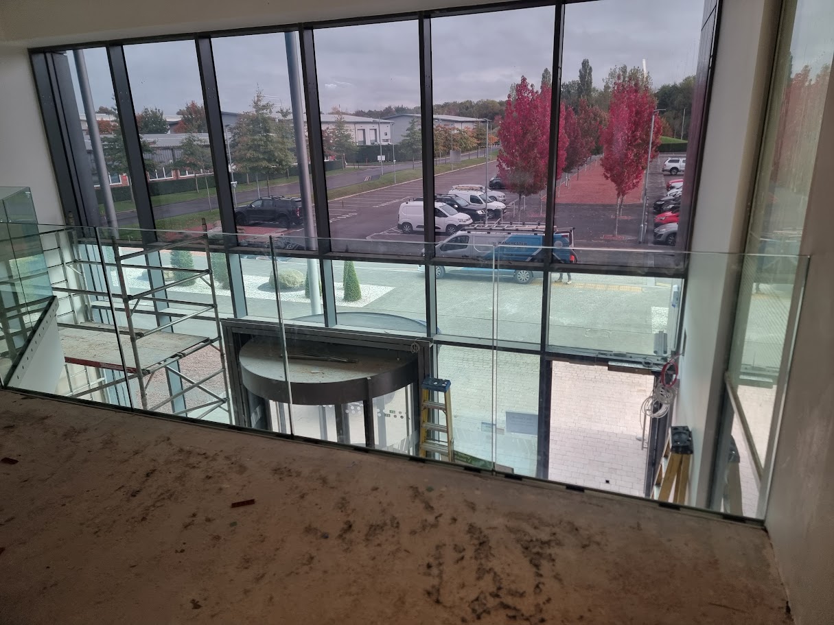 Frameless glass mezzanine in a double-height office lobby — Manchester Balustrades installation