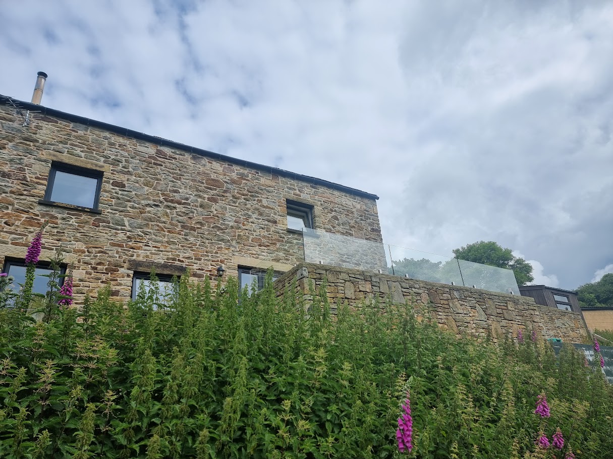 A frameless glass terrace at a New Mills farmyard conversion — further view of the completed installation