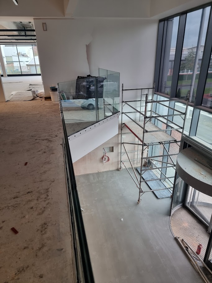 Frameless glass mezzanine in a double-height office lobby — further view of the completed installation