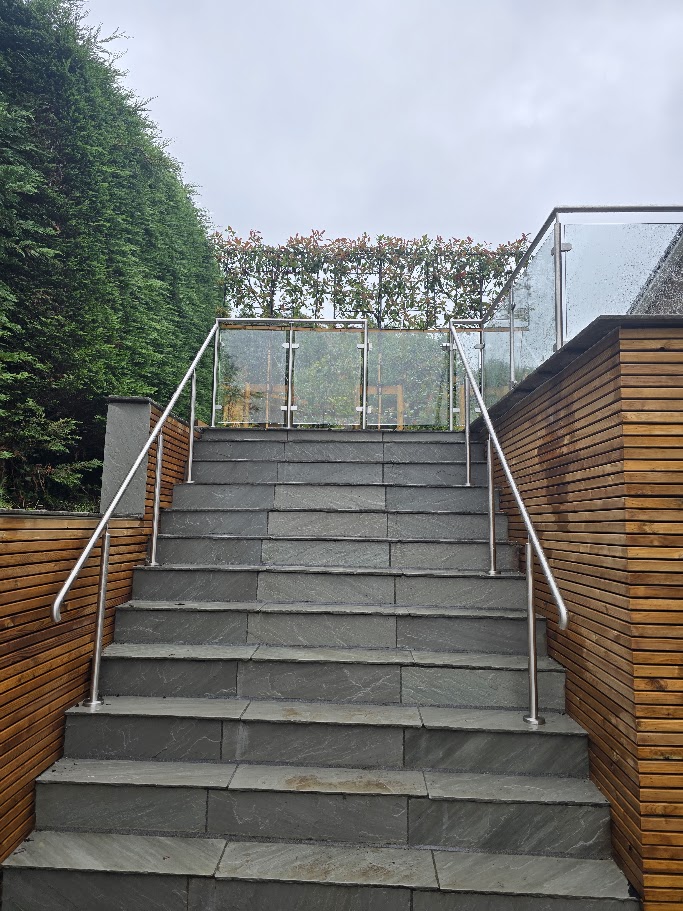 Stainless steel post and glass balustrade on a raised garden terrace — further view of the completed installation