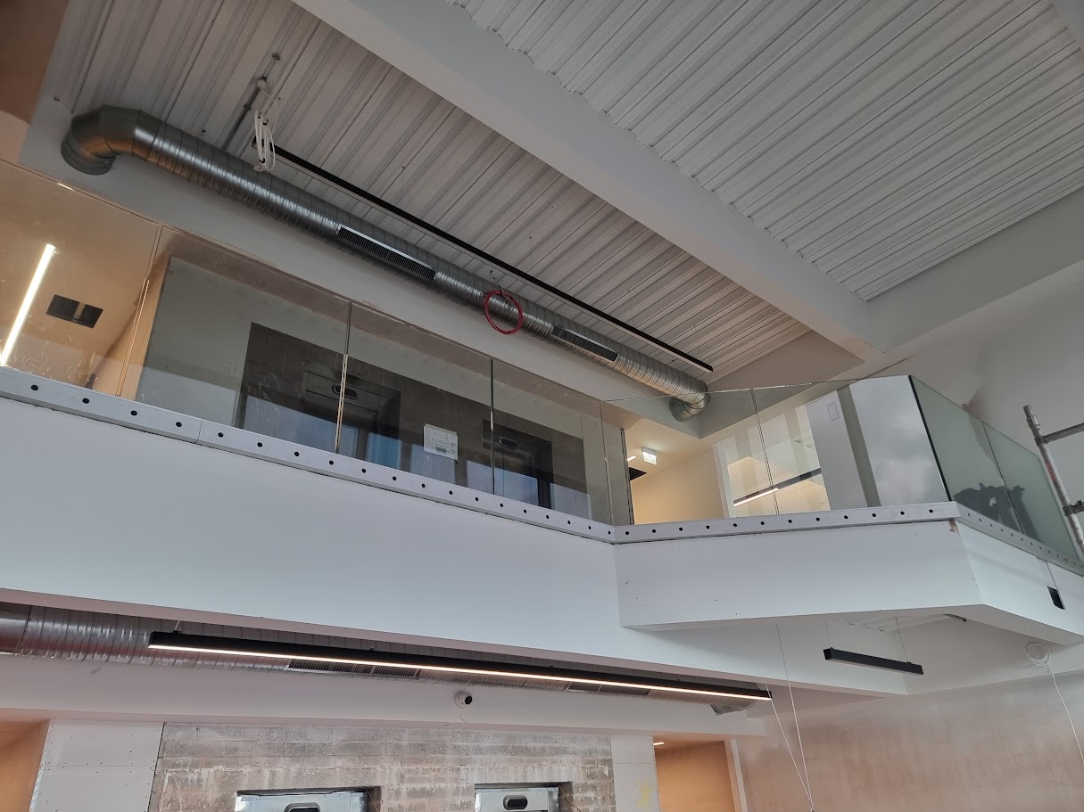 Frameless glass mezzanine in a double-height office lobby — further view of the completed installation