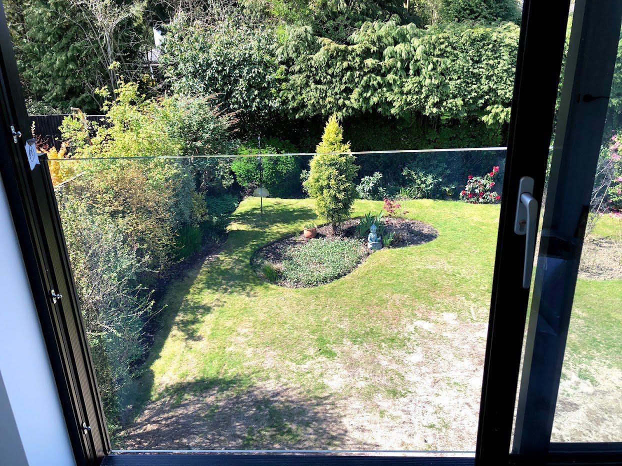 Juliette balcony glass balustrade installed by Manchester Balustrades above a landscaped garden